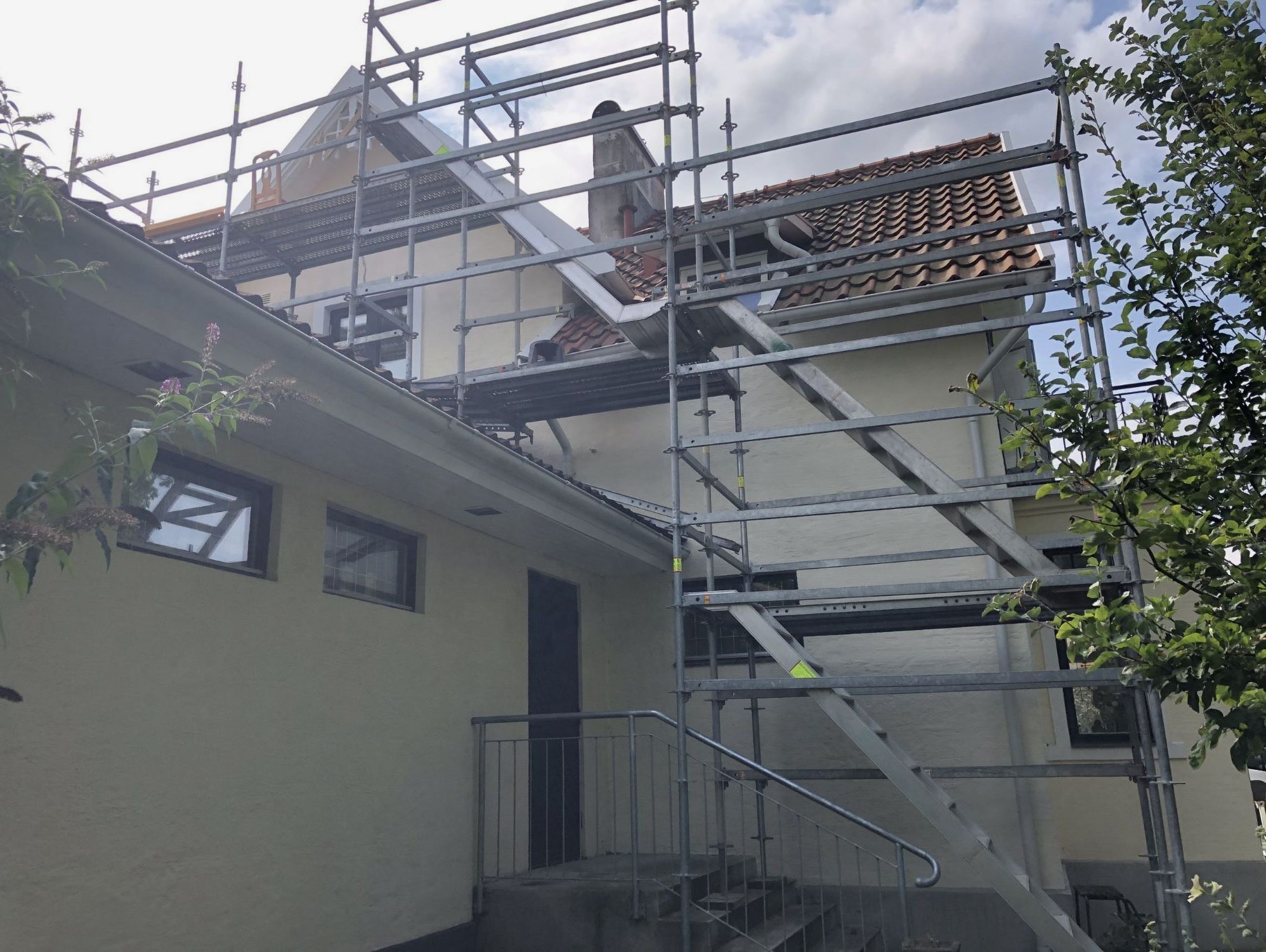 Byggställning monterad längs bostadshus med trappa.